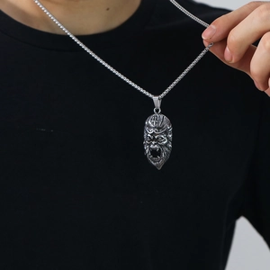 Detailed close-up of a vintage silver Monkey King pendant on a steel box chain necklace