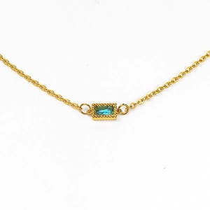 Macro detail of gold necklace featuring a rectangular teal zircon pendant in beaded bezel