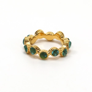 Vista detallada de un anillo vintage ondulado dorado con piedras redondas color cian oscuro