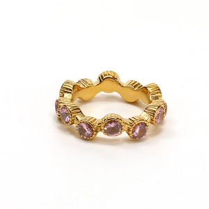 Vista macro de anillo ondulado dorado con diamantes rosa redondos y engaste texturizado