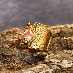 Makro-Detail eines breiten Gold-Titan-Rings mit rosa Edelstein und Vintage-Texturen