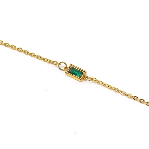 Close-up of gold chain with rectangular green gemstone pendant and beaded edge detail