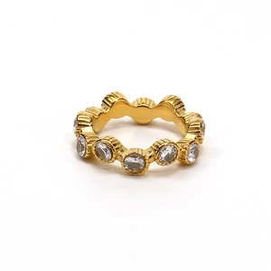 Detalle de anillo dorado con bordes ondulados y cristales de circonita redondos engastados