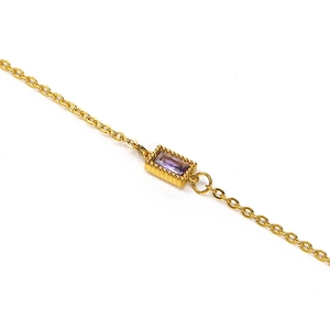 Macro view of a rectangular purple gemstone set in a beaded gold stainless steel pendant