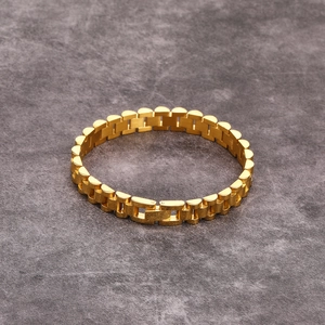 Minimalist gold titanium steel watch-band style bracelet on a textured stone surface
