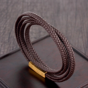 Détail d'un bracelet multicouche en cuir tressé marron foncé avec fermoir magnétique doré