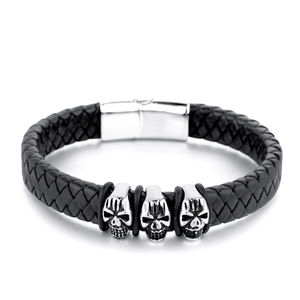 Detailansicht eines geflochtenen schwarzen Lederarmbands mit drei silbernen Totenköpfen