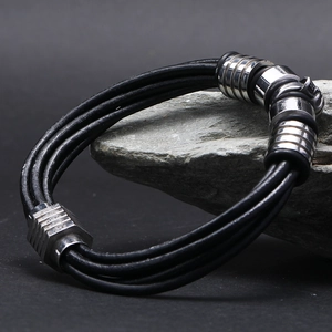 Gros plan d'un bracelet en cuir noir multibrins avec des anneaux en métal sur une pierre