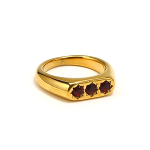 Dettaglio macro di anello placcato oro 18k con tre zirconi rossi incastonati a stella