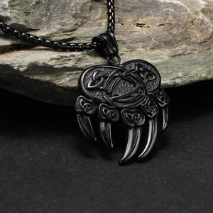 Macro detail of Nordic bear paw pendant with Celtic knot patterns on a rock surface