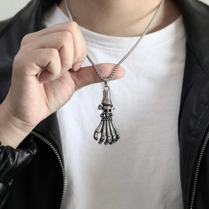 Detailed close-up of a vintage punk skeleton hand pendant necklace on a leather jacket