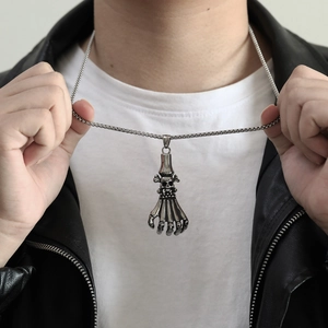 Gothic skull and skeleton hand pendant necklace on male model wearing leather jacket