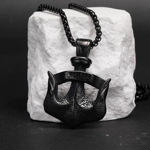 Vue détaillée du pendentif ancre en acier noir avec gravure China sur un socle en pierre