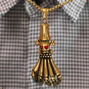 Detail of gothic gold skeleton hand pendant with red crystal eyes on a matching gold chain