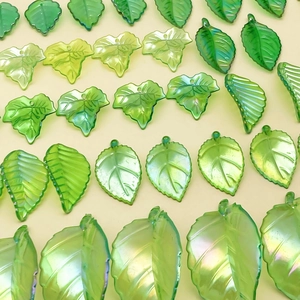 Macro view of iridescent acrylic maple leaf charms with pre-drilled holes for DIY jewelry