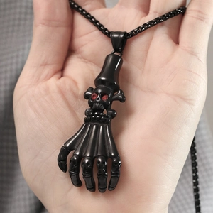 Macro detail of gothic skull pendant with red gemstone eyes and bone fingers