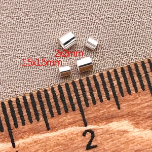 Nahaufnahme von 1,5 mm und 2 mm Silber-Abstandshalterperlen mit Lineal zum Maßstab
