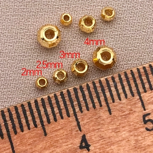 Dettaglio macro di perline distanziatrici sfaccettate placcate oro 18K da 2mm a 4mm