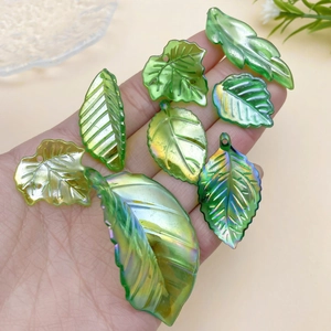 Macro detail of AB coated green acrylic leaf charms with iridescent finish and top drill hole