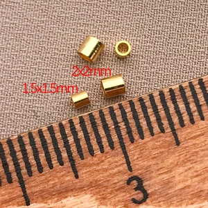 Detaillierte Makroansicht von 1,5 mm und 2 mm 18K vergoldeten Quetschperlen mit Skala