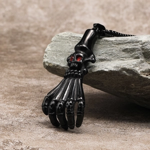 Close-up of a punk skull hand pendant in matte black finish with red gemstone eyes