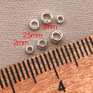 Macro view of 2mm 2.5mm and 3mm silver metal positioning beads on textured fabric