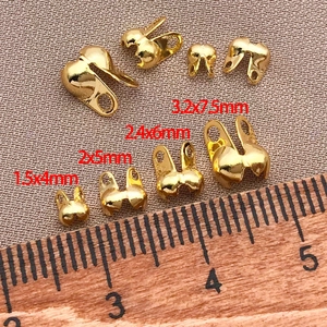 Macro view of 18K gold-plated double-hole clam shell bead tips in four sizes with ruler