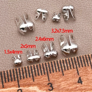 Macro shot of silver metal fold-over crimp beads in four sizes for DIY jewelry making