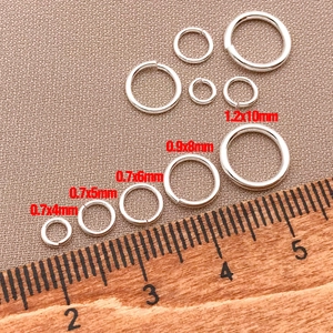 Detailed view of silver jump rings in various sizes with a ruler for size reference