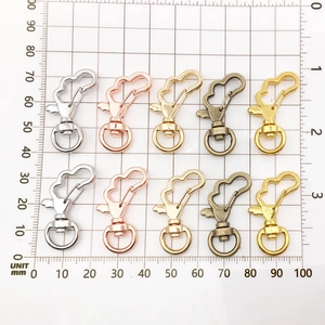 Detail van diverse metalen karabijnsluitingen in vijf kleuren op een ruitjesmat