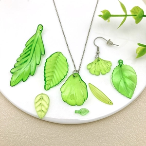 Set aus lichtdurchlässigen grünen Acryl-Blattanhängern für DIY-Schmuck auf weißem Display