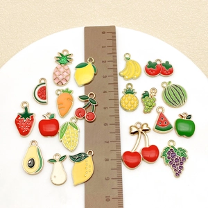 Detailed assortment of colorful enamel fruit pendants with a ruler for size reference