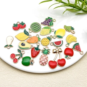 Detailed close-up of colorful enamel fruit and vegetable charms in a ceramic bowl