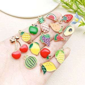 Detailed close-up of mixed enamel fruit and vegetable charms in a hand-held display