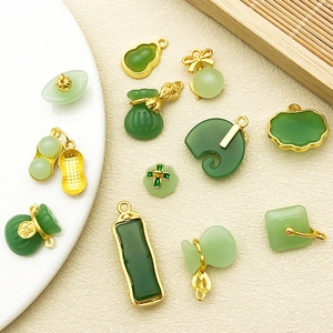 Assorted green faux jade pendants with gold metal trim and traditional Chinese motifs