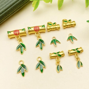 Detailed macro view of green enamel bamboo leaf charms and golden lucky charms for jewelry