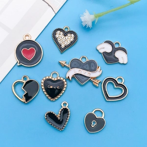 Nove diversi ciondoli a cuore in smalto nero con base in lega dorata su blu