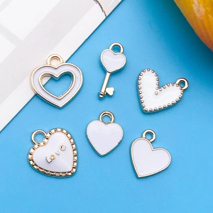 Dettaglio dei ciondoli a cuore in smalto bianco con bordo dorato per accessori gioielli DIY