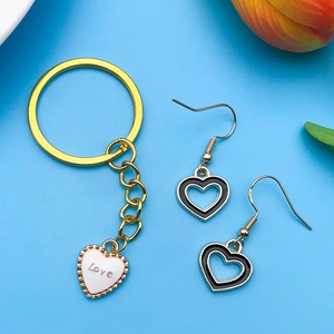 Dettaglio portachiavi dorato con cuore bianco e orecchini cuore in smalto nero