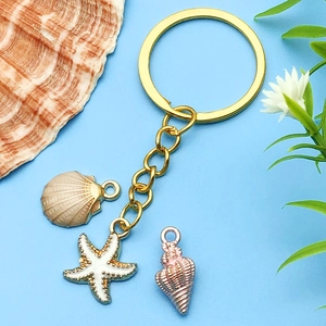 Détail d'un porte-clés marin doré avec étoile de mer et coquillage sur fond bleu océan