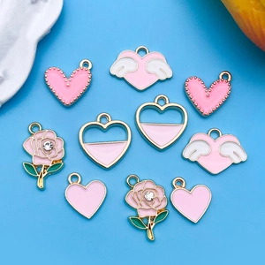 Détail des breloques en forme de cœur et rose en émail rose et blanc avec bord doré