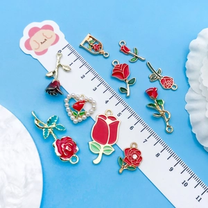 Detailed macro view of enamel rose charms and pearls against a blue background with scale