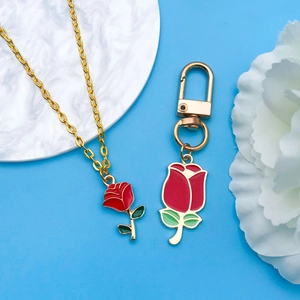 Detail of red rose charms with green leaves on gold chain and spring ring keychain