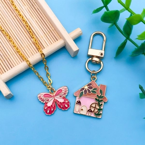 Detail von rosa Schmetterling-Anhänger und Blumenhaus-Charm mit Goldlegierung