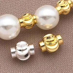 Macro shot of 18k gold-plated spiral lantern spacer beads with white pearls on fabric