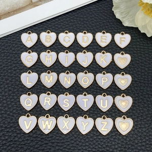 Macro-weergave van 26 wit-gouden hartvormige bedels met A-Z letters voor DIY sieraden maken
