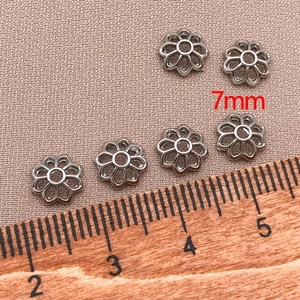 Dettaglio di copriperle a fiore argento da 7mm per gioielli fai da te su scala