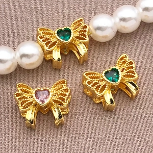 Macro detail of 18K gold bow spacer charms with pink and green zircon on pearl necklace