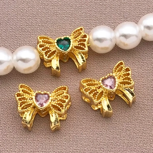 Detail of 18K gold-plated bow charm with heart zirconia on a white pearl necklace