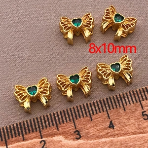 Macro shot of five 8x10mm 18K gold-plated bow beads with green heart zircon stones